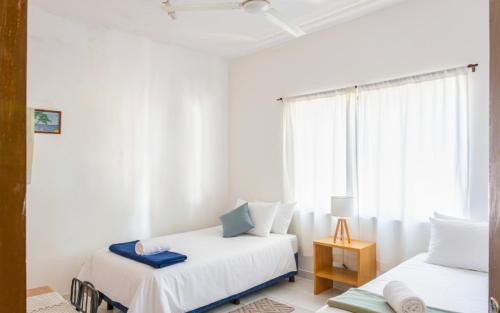 two beds in a white room with a window at Casa Eva, rústica y cálida familiar in Asuncion