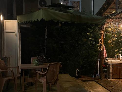 a patio with a table and a green umbrella at Tsitadel in Zugdidi