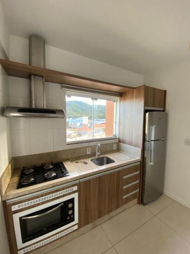 uma cozinha com um fogão, um lavatório e um frigorífico em Apartamento de 2 quartos equipado em Imbituba sc em Imbituba