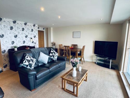 a living room with a black leather couch and a table at Pears Suite - 1 Bedroom - Sleeps 2 in Whitehaven