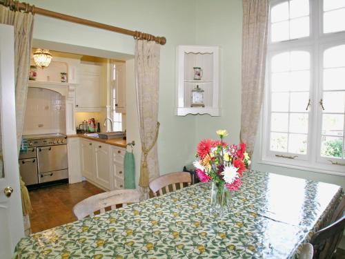 eine Küche mit einem Tisch mit einer Vase mit Blumen darauf in der Unterkunft Luppincott Chambers - Hpps in Bideford