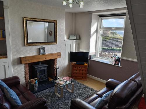 a living room with a fireplace and a television at Copper Mine Cottage in Llandudno