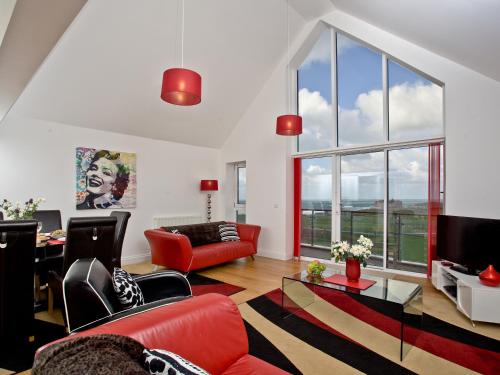 a living room with red furniture and a large window at Bredon Court, Poseidon Penthouse in Newquay