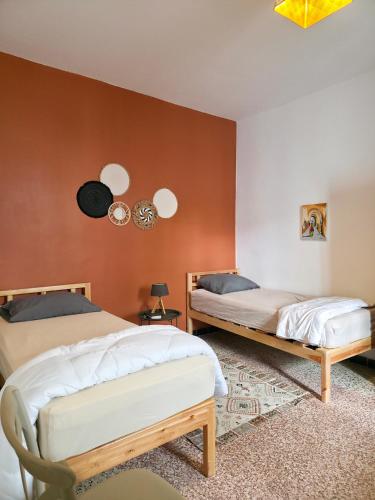 two beds in a room with orange walls at Les Sables Bleus in Le Kram