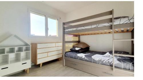 a bedroom with two bunk beds and a window at La perle rare in Le Barcarès