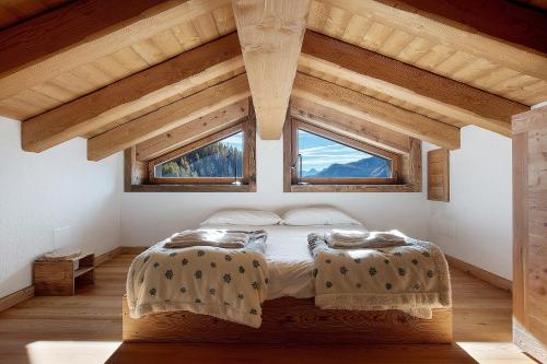 a bedroom with a bed and two windows at Casa Promindoz in Valtournenche