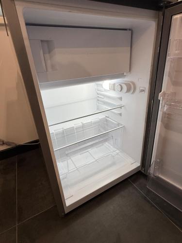 an empty refrigerator with its door open in a kitchen at Flat In the heart of Kaunas city center in Kaunas