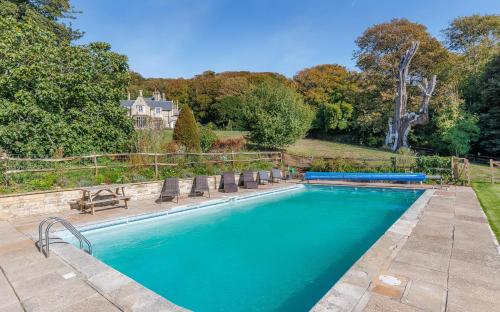 Isle of WightにあるEast Dene Estateの背景に家があるスイミングプール(椅子付)