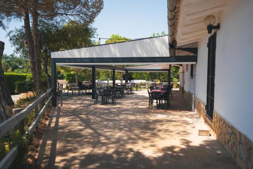 a patio with tables and chairs under a roof at HolaCamp Palamós in Vall-Llobrega