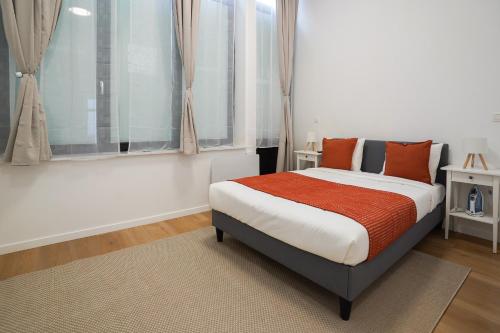 una camera da letto con un letto con cuscini arancioni e una finestra di Appartment St guidon 1 a Bruxelles