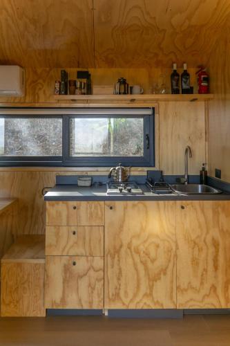 a kitchen with wooden cabinets and a sink and a window at Cabins entre bosques y viñedos con vistas al valle - Tucu cabins in Maipo