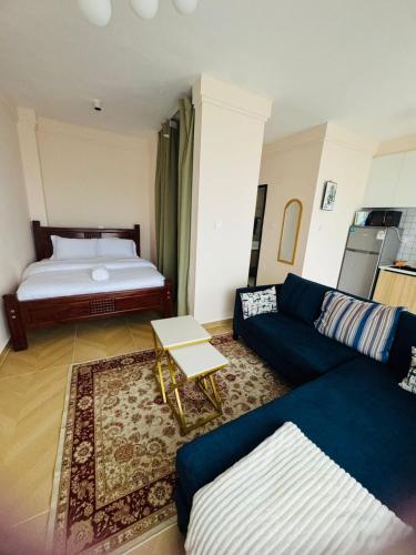 a living room with a blue couch and a bed at Artesano one bedroom cozy and comfortable in Syokimau