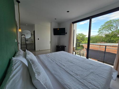 a bedroom with a white bed and a large window at View Theras Hotel in Doradal