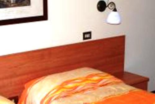 a bed with a wooden head board and a light at Hotel Delle Alpi in Sondalo