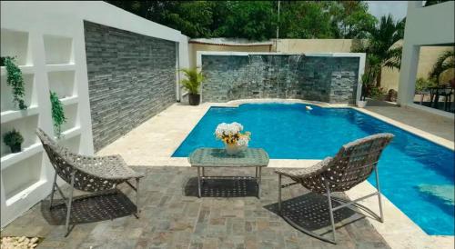 a swimming pool with two chairs and a table at Villa Lujosa en Boca Chica in Cuevas