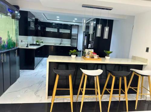 a kitchen with black cabinets and a island with bar stools at Villa Lujosa en Boca Chica in Cuevas