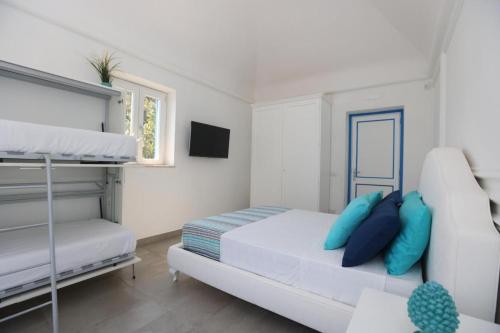 Un dormitorio blanco con una cama con almohadas azules. en Villa Dei in Positano - Camere, en Positano