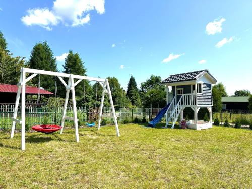 Gniazdo Sikorek في Wieniec: ملعب مع أرجوحة ومنزل