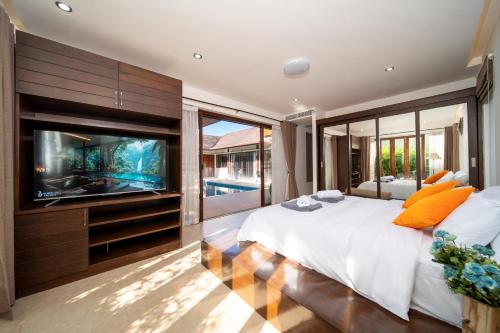 ein Schlafzimmer mit großem Bett und Flachbildfernseher in der Unterkunft Tropical Pool Villa Thai-modern Villa with an OFFICE in Phuket