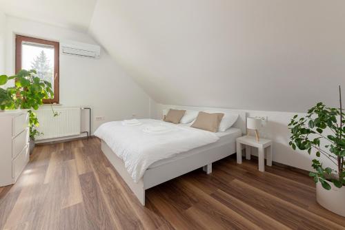 a white bedroom with a bed and a potted plant at LOGAR Apartments in Preddvor
