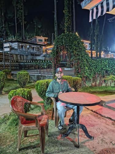 un hombre sentado en una mesa al lado de una mesa en The highlight stay, en Uttarkāshi