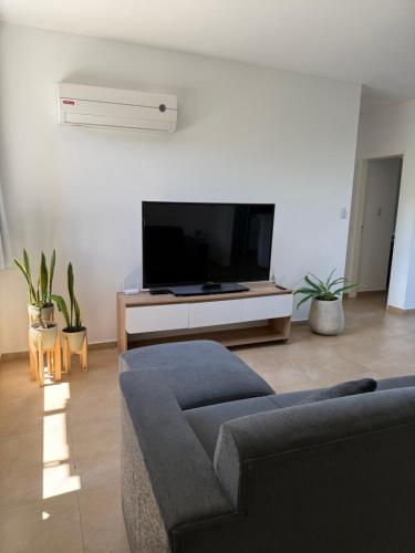 a living room with a couch and a flat screen tv at Departamento Lago Los Molinos in Villa Ciudad de America