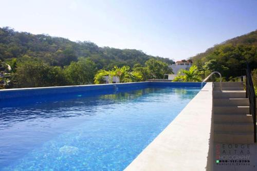 ein großer Pool mit blauem Wasser und Bäumen in der Unterkunft TerraCondos Loft 203 & 204 in Bahías de Huatulco