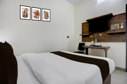 a bedroom with a bed and a desk with a television at Hotel O Shad Residency in Patna
