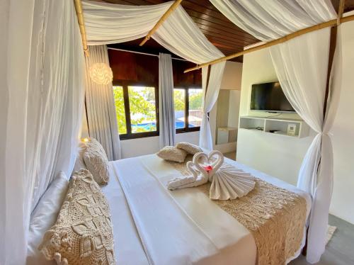a bedroom with a white bed with a canopy at Pousada Encontro das Águas in Maragogi
