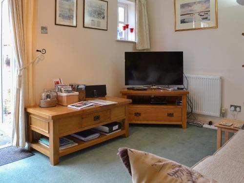 ein Wohnzimmer mit einem TV auf einem Holztisch in der Unterkunft Trentham Cottage in Snettisham