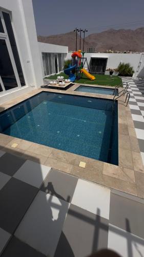 una piscina al costado de una casa en شالية القمر, en Wāsiţ