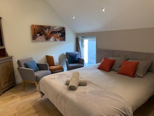 ein Schlafzimmer mit einem großen Bett und zwei Stühlen in der Unterkunft Le Verger Des Pierres Blanches,11 chambres,11 wc, 8 sdbs,pool chauffée 11 m 35p in Mont-près-Chambord