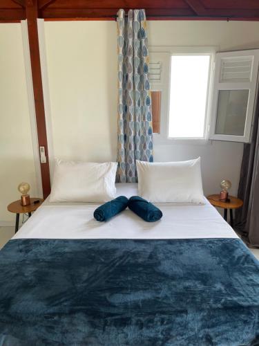 a bed with two blue shoes sitting on top of it at Les gîtes Lanmou 1 in La Désirade