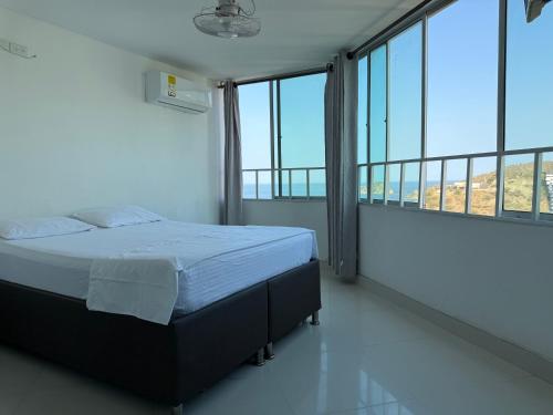 ein Schlafzimmer mit einem Bett in einem Zimmer mit großen Fenstern in der Unterkunft Apartamento en el Rodadero in Santa Marta