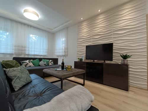 Una sala de estar con un sofá y un televisor. en B4 Garden ***, en Siófok