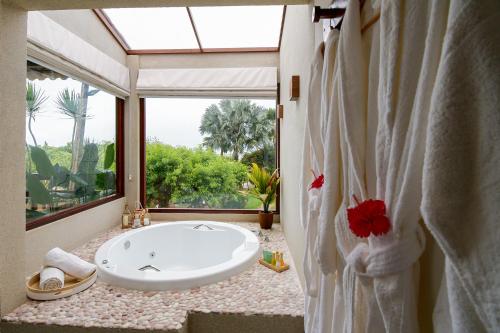 a bathroom with a large tub and a large window at Pousada Encontro das Águas in Maragogi
