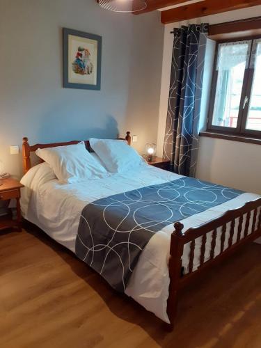 a bedroom with a bed with a blue blanket and a window at Gîte ETXOLA in Saint-Étienne-de-Baïgorry