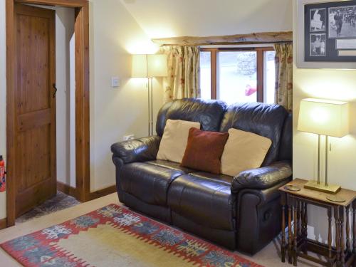 a leather couch in a living room with two lamps at Yew Tree Bothy in Old Brampton