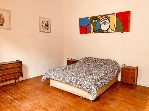 a bedroom with a bed and a painting on the wall at La Mancha Art Hostel in Valparaíso