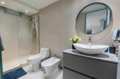 a bathroom with a sink and a toilet and a mirror at Isla | The Sunset Abode in Ocean Club, Rincón in Corcega