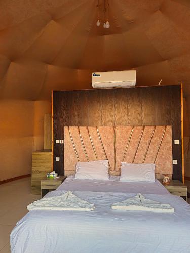 a bedroom with a large bed with a wooden headboard at SILENT SKY lUXURY CAMP in Wadi Rum