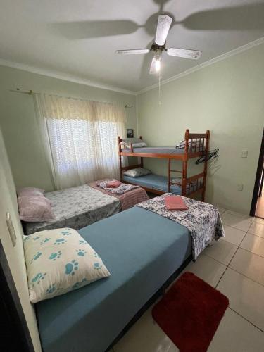 a bedroom with two beds and a table with a fan at Hostel e Pousada Vó Lili in Joinville