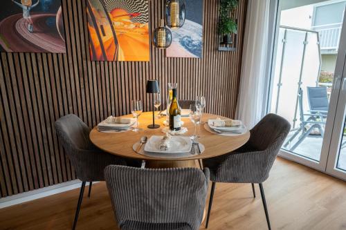 a wooden table with chairs and a bottle of wine at Modernes Apartment - Basel, Kur & Golf in Bad Bellingen