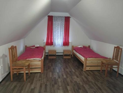 a attic room with two beds and red curtains at NADENKA & MGR Vendégház in Alsótelekes