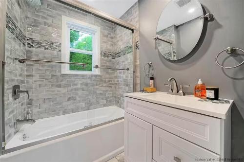 a bathroom with a sink and a tub and a mirror at New Leeds listing Near Graces diner and Hudson! in Catskill