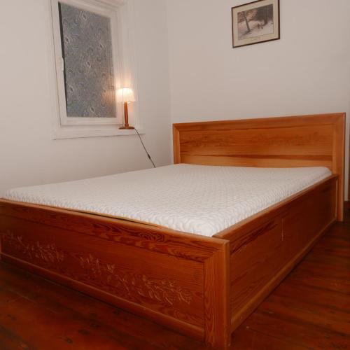 a wooden bed in a room with a window at Namelis 1954 in Švenčionėliai