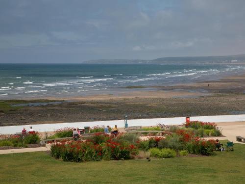 een uitzicht op een strand met bloemen en de oceaan bij Apartment 5 Latitude 51 Westward Ho! in Westward Ho