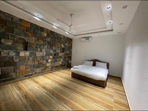 a bedroom with a bed and a brick wall at Climbing Guest House Jebel Shams in Dār Sawdāʼ