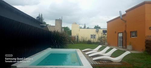 a group of white chairs sitting next to a swimming pool at DUPLEX ATARDECERES in Chascomús