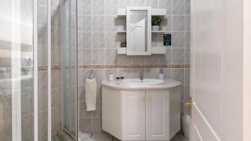 een badkamer met een witte wastafel en een douche bij Fly Me To The Moon Guesthouse in Mosselbaai